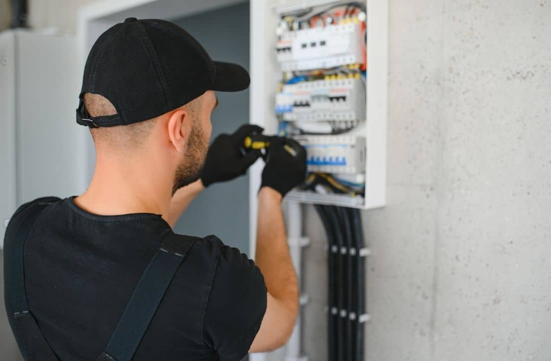 Électricien professionnel devant un tableau électrique dans une habitation.