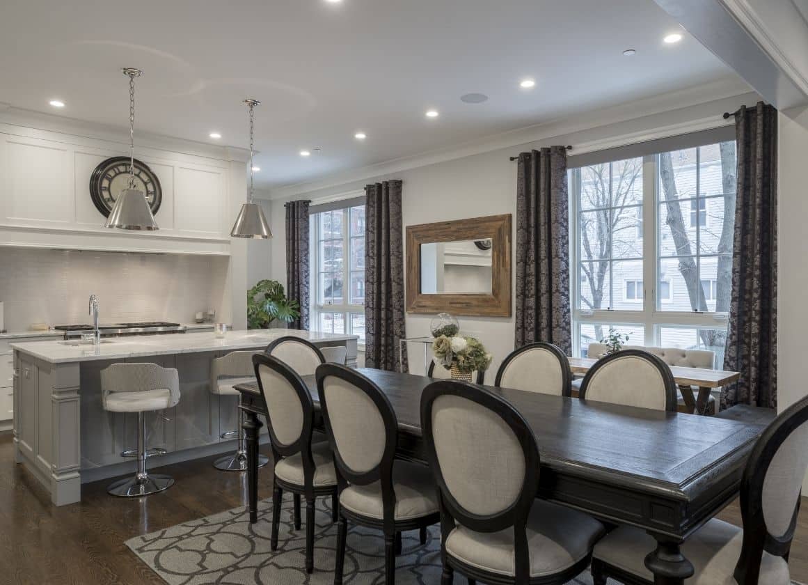 Salle à manger et cuisine ouvertes équipées de spots encastrés et de luminaires suspendus pour un éclairage intérieur moderne et confortable.